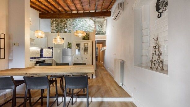 A modern kitchen with a wooden dining table, black chairs, pendant lights, and a view of the living area. - Giglio Celeste apartment in Florence by Mmega (Firenze)