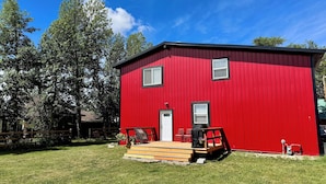 Un bâtiment rouge avec une porte d’entrée, deux fenêtres et un petit porche avec des marches.