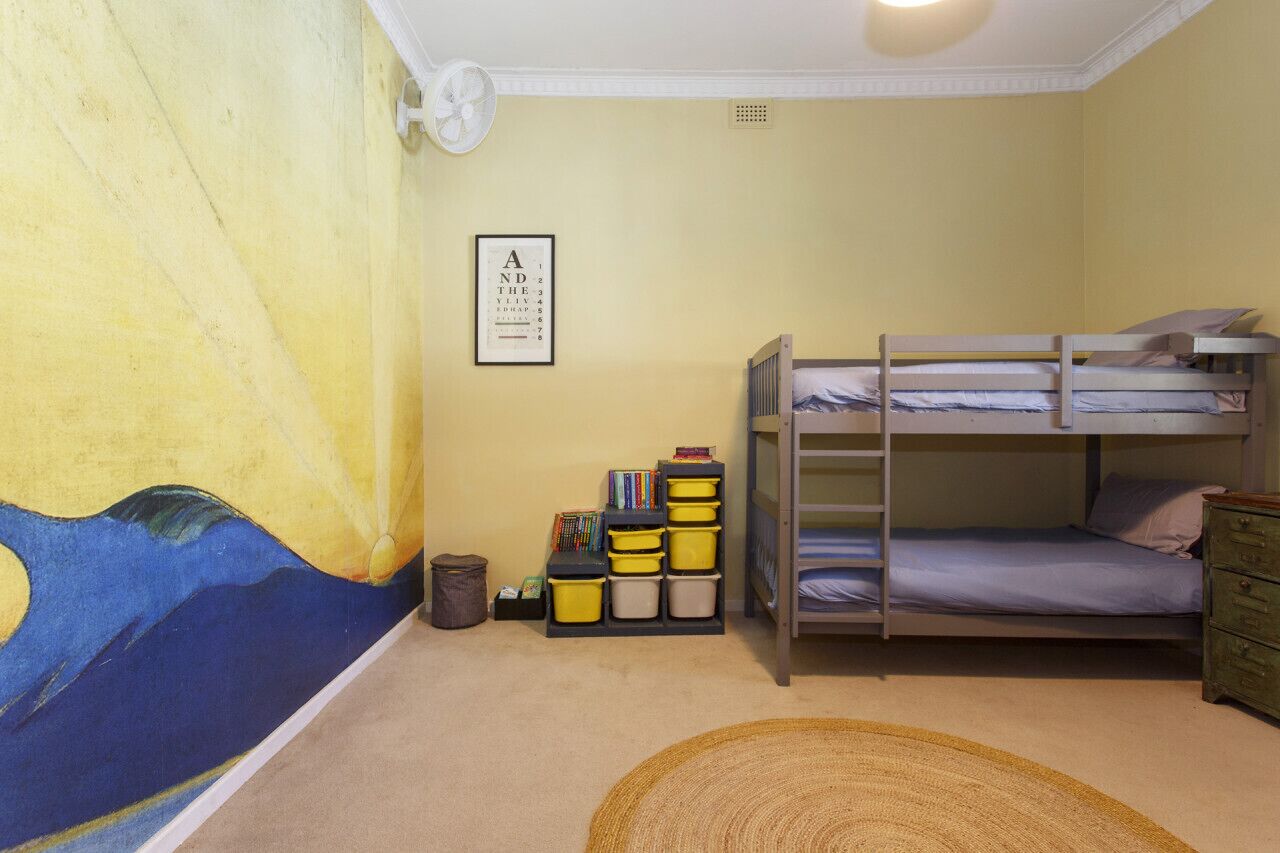 Une chambre avec des lits superposés, une bibliothèque et une peinture murale.