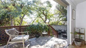 A wooden deck with a rocking chair, potted plants, and a staircase leading to an upper level. - Lilly`s Cottage - 3bdrm Heritage House, South Fremantle (South Fremantle)