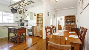 Cuina amb armaris de fusta, una taula de dinar amb caires i un lampadari.
