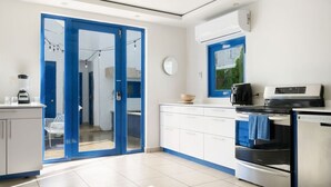 A modern kitchen with a blue-framed sliding door leading to a balcony, a built-in oven, and a coffee machine.