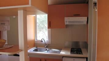 Een koelkast, een magnetron, een kookplaat, kookgerei, borden en bestek