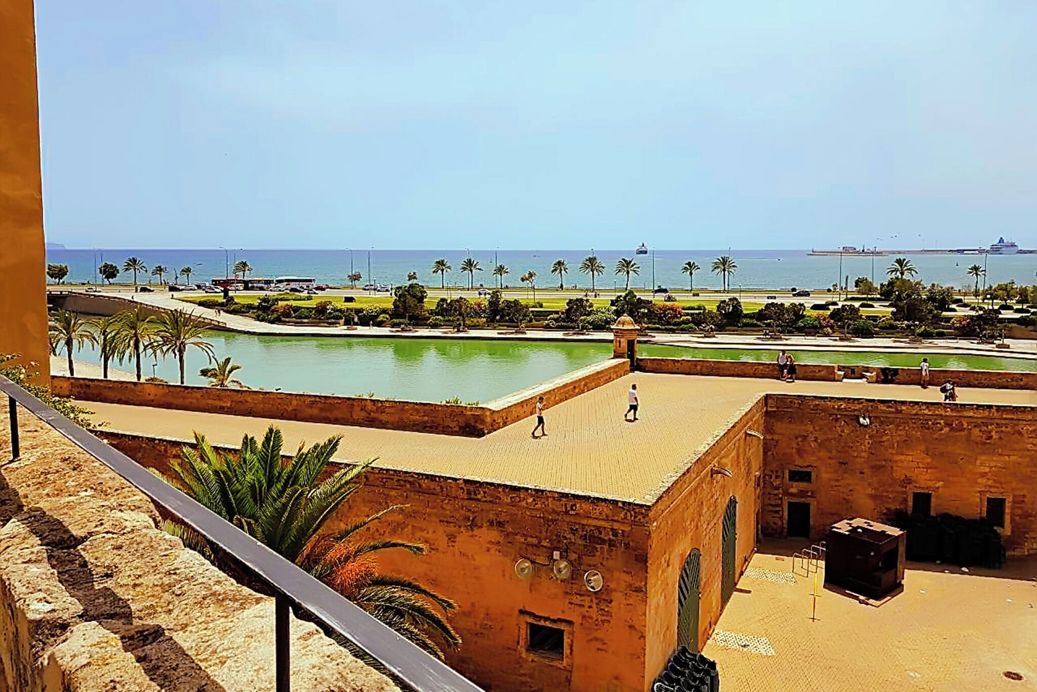 Blick auf die Küste mit Strand, Palmen und einem Schiff in der Ferne.