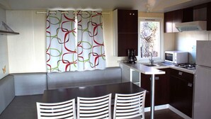 A compact kitchen with a dining area, including a table, chairs, and a built-in bench.