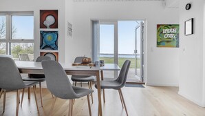 A modern dining area with a large table, four grey chairs, and artwork on the walls. - Stunning home in Holbæk with kitchen (Holbæk)