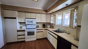 A compact kitchen with a microwave, stove, and dishwasher. - Three Bedroom House Lake George (Lake George)