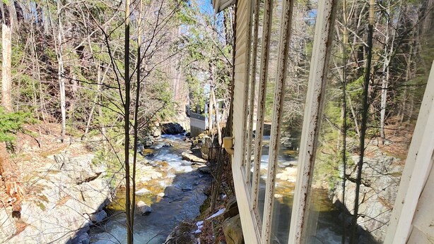 A cabin with a view of a stream and surrounding trees. - Three Bedroom House Lake George (Lake George)