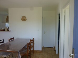 A dining area with a table and chairs, a hanging lamp, and a door leading to another room.