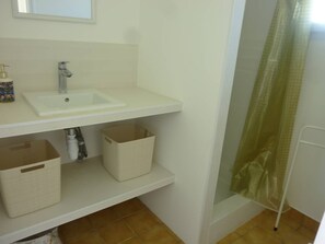 A bathroom with a white sink, a mirror above it, and a shower curtain. There are two storage baskets under the sink.
