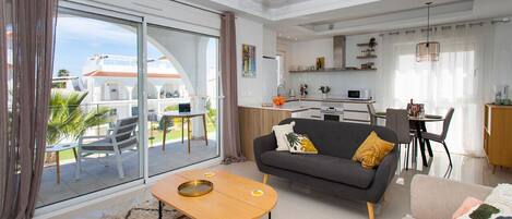A modern living room with a sofa, coffee table, and a dining area with chairs.