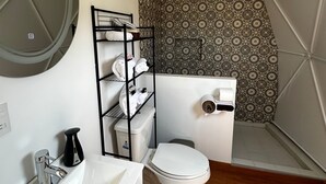 A bathroom with a white sink, a toilet, a shower, and a patterned wall. - ixkapada glamping  (Ixtapan de la Sal)