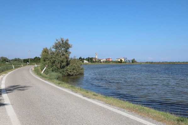 Une route sinueuse longe un plan d’eau, et on aperçoit une église au loin.