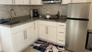 A modern kitchen with white cabinets, a stainless steel refrigerator, a microwave, a coffee maker, and a kettle. - Feel like in home in this beautiful guest casita with mountains views. (Tucson)