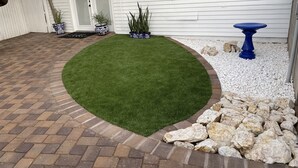 A landscaped patio with a green lawn, brick pathway, decorative rocks, and potted plants. - Feel like in home in this beautiful guest casita with mountains views. (Tucson)