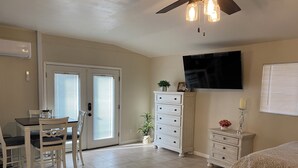 A bedroom with a bed, a dresser, a desk with chairs, a television, and a ceiling fan. - Feel like in home in this beautiful guest casita with mountains views. (Tucson)