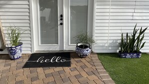A white door with a glass panel, a black doormat with "hello" written on it, and two potted plants on either side of the door. - Feel like in home in this beautiful guest casita with mountains views. (Tucson)