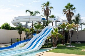 A water park with multiple water slides and palm trees. - Nice villa located in LES TAMARIS, Airco, 2 bedrooms, 5 people, Wifi, 500 from the beach of... (PORTIRAGNES)