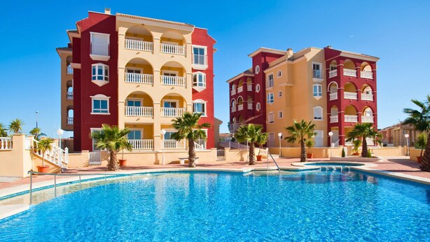 Un hôtel doté d’une piscine, avec des bâtiments à plusieurs étages, des balcons et des palmiers.