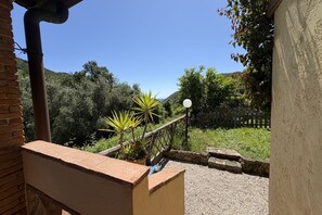 Un balcón con vista a un jardín y colinas.