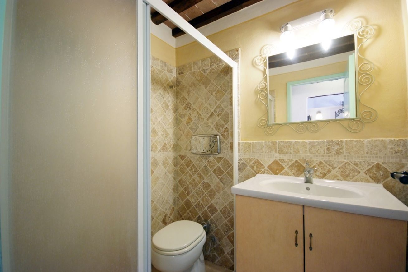 A bathroom with a toilet, sink, and mirror.