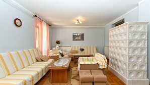 A living room with striped sofas, a coffee table, a side table with flowers, a radiator, and a decorative wall unit. - House 2322/109111 (Istria - Pula), 1500m from the beach (Pula)