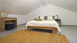 Une chambre à coucher comprenant un lit, un bureau, une chaise, un miroir et une table de chevet avec une lampe.
