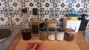 A kitchen counter with various items including bottles, jars, and a package of thread.