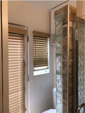 A bathroom with a toilet, a shower with glass doors, and two windows with blinds. - Panoramic Ocean Views, 3Bdr/7Beds/2Ba, Hot tub, Patio, AC, Best Mission Location (San Diego)