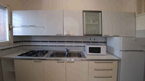 Eine Küche mit Gasherd, Spüle, Mikrowelle und Kühlschrank.