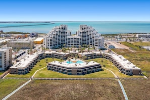 A hotel with a central courtyard, multiple floors, and a view of the sea.