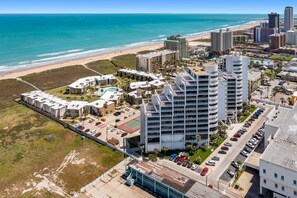A coastal hotel with multiple buildings, a parking lot, and a beach view. - Sunchase IV #506 | Beachfront Condo • Gulf & Bay Views • Resort Pools​​​​​​​ (South Padre Island)