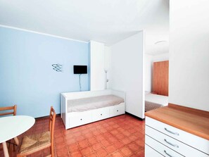 A room with a bed, a desk, a chair, and a TV.
