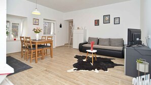 A modern living room with a dining area, a sofa, a TV, and a cowhide rug.