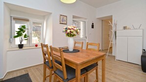 A dining area with a wooden table, chairs, a vase of flowers, and a white ceiling light.