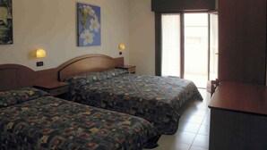 Een hotelkamer met twee bedden, een bureau, een stoel, een raam met uitzicht en wandlampen.