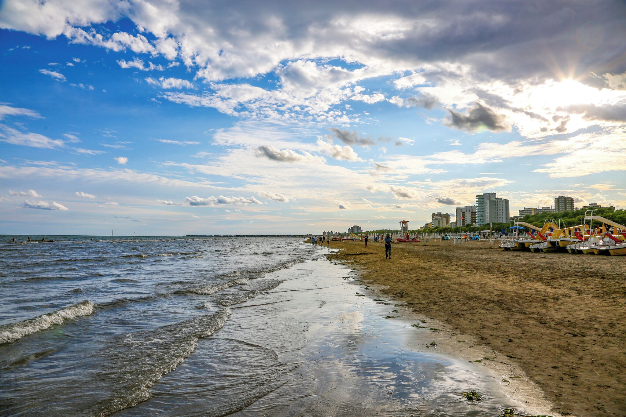 Une plage avec des vagues, un rivage sablonneux et des bâtiments en arrière-plan.