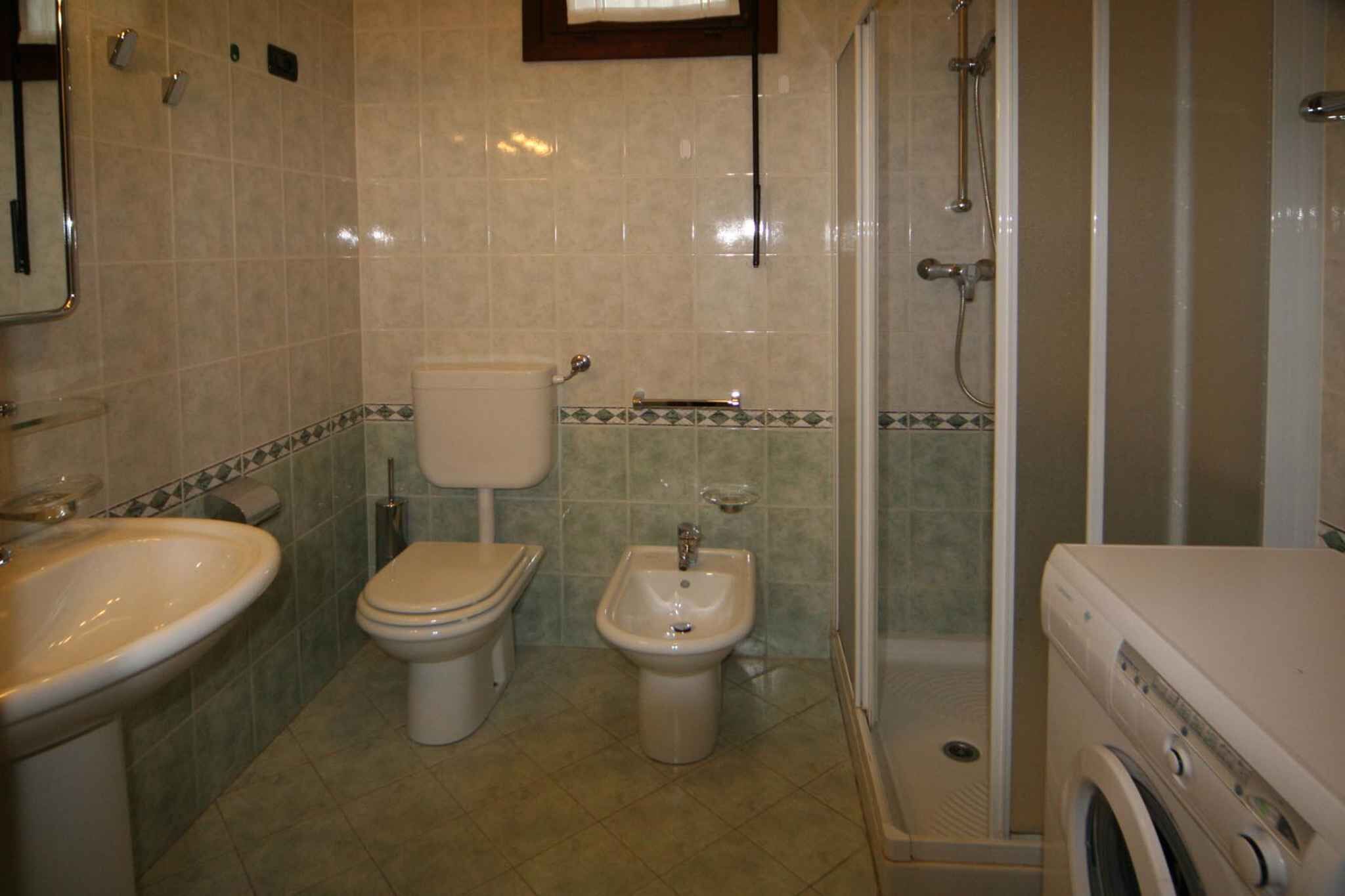 Un baño con inodoro, bidé, lavabo y lavadora.