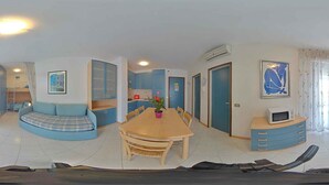 A compact living space with a sofa, dining table, and kitchenette. - Holiday apartment with air conditioning and balcony (Lignano Sabbiadoro)
