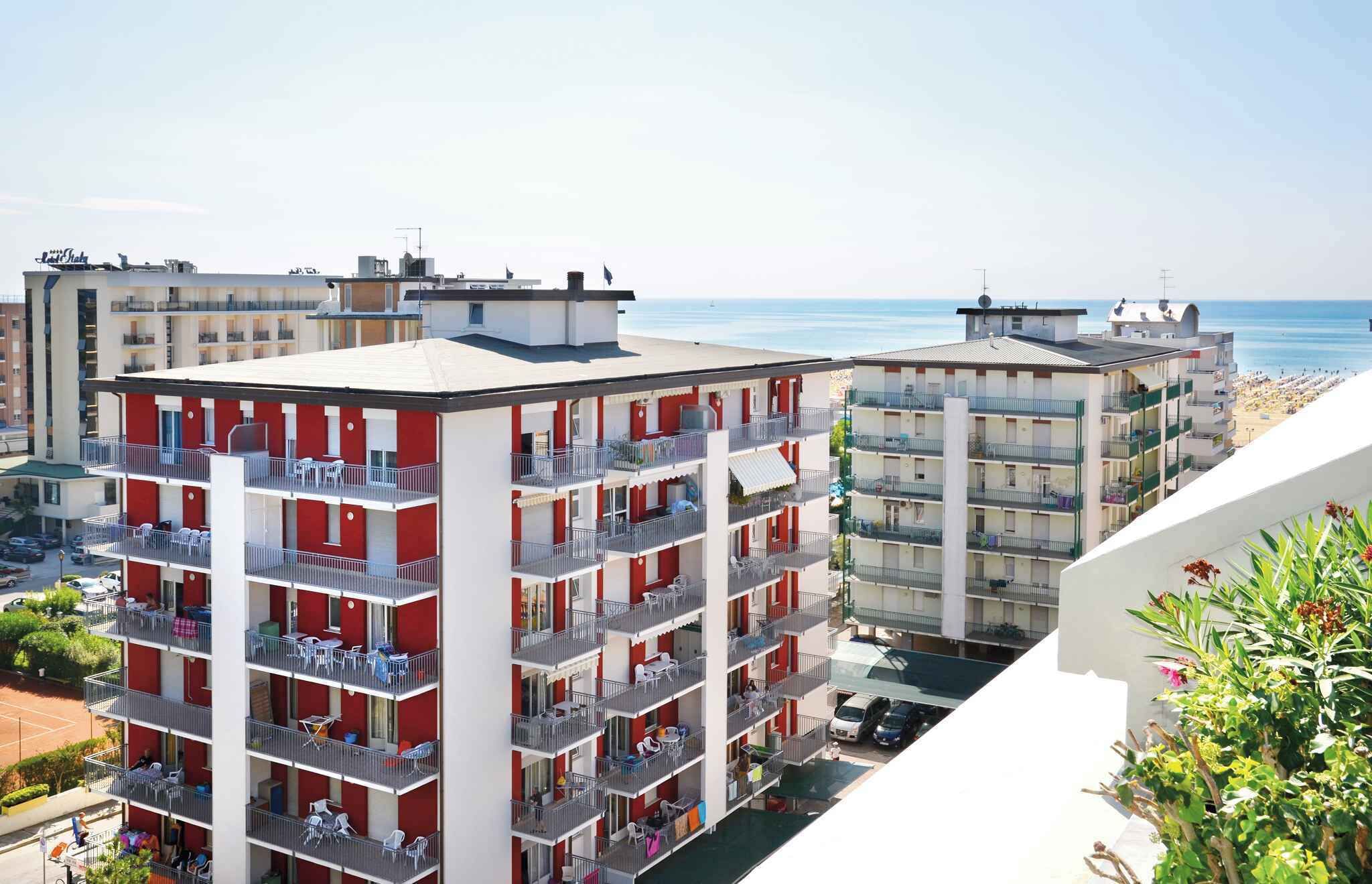 Ein mehrstöckiges Hotel mit Balkonen, Blick auf den Strand und einem Parkplatz.