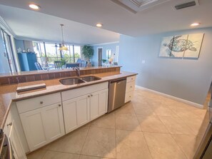 A kitchen with a double sink, white cabinets, and a dishwasher.