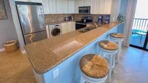 Una cocina moderna con una isla grande, electrodomésticos integrados y vistas al exterior.