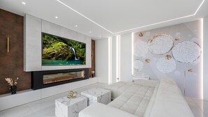 A modern living room with a large flat-screen TV, a fireplace, a white sofa, and decorative wall art. - Lovely home in Tribunj with private swimming pool, can be inside or outside (Tribunj)