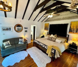 Quarto com cama, sofá, espelho e ventoinha no teto.