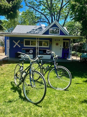 Uma casa com fachada azul e uma placa de 'Welcome'. Duas bicicletas estão estacionadas em frente.