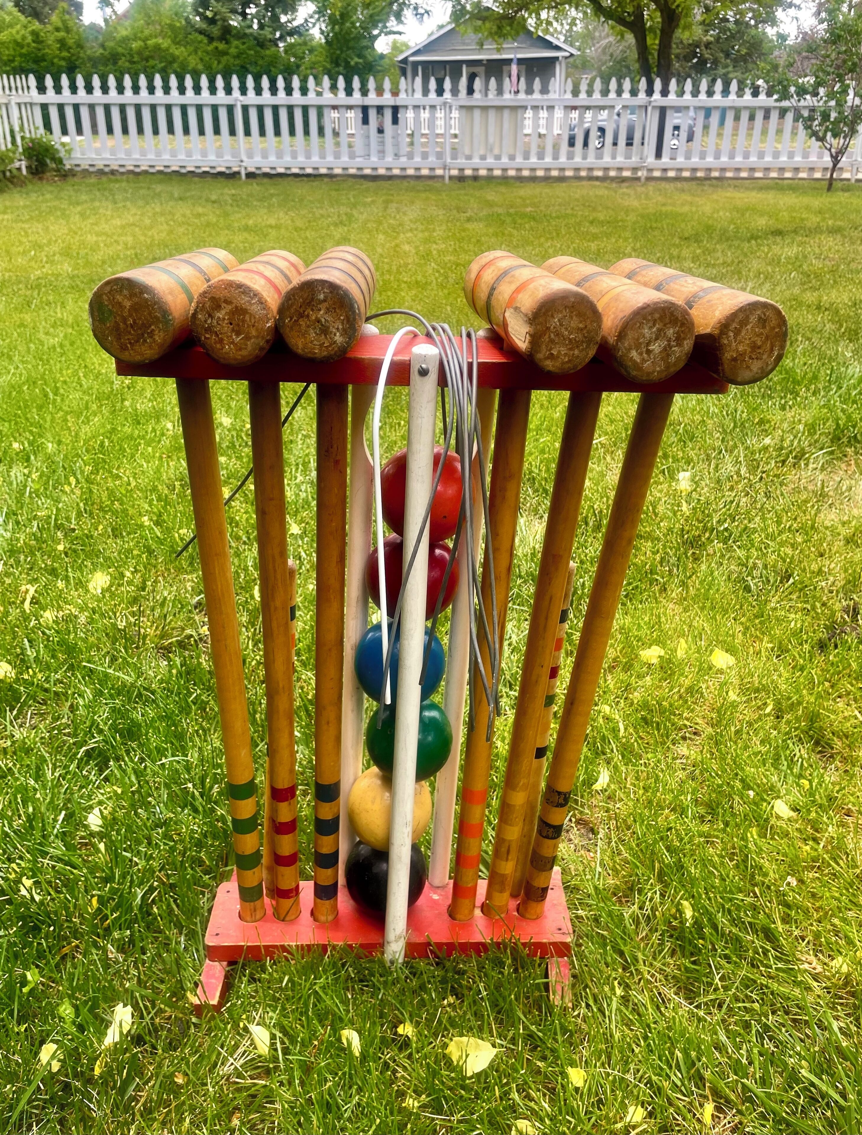 Un soporte de madera para bates de cricket con varios bates y pelotas.