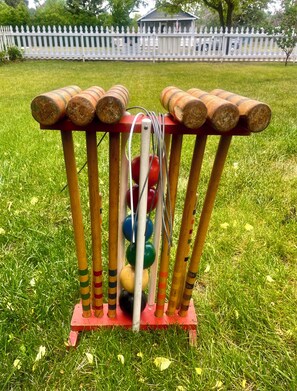 Un soporte de madera para bates de cricket con varios bates y pelotas.