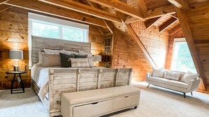 A log cabin bedroom with a large bed, a sofa, and a bench. - Waverly Lakehouse - private cabin, lake view, close to 
Old Waverly/Mossy Oak (West Point)