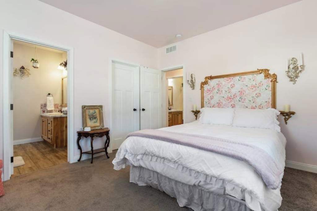 Un dormitorio con una cama grande, un aparador, un tocador y una puerta que da a otra habitación.