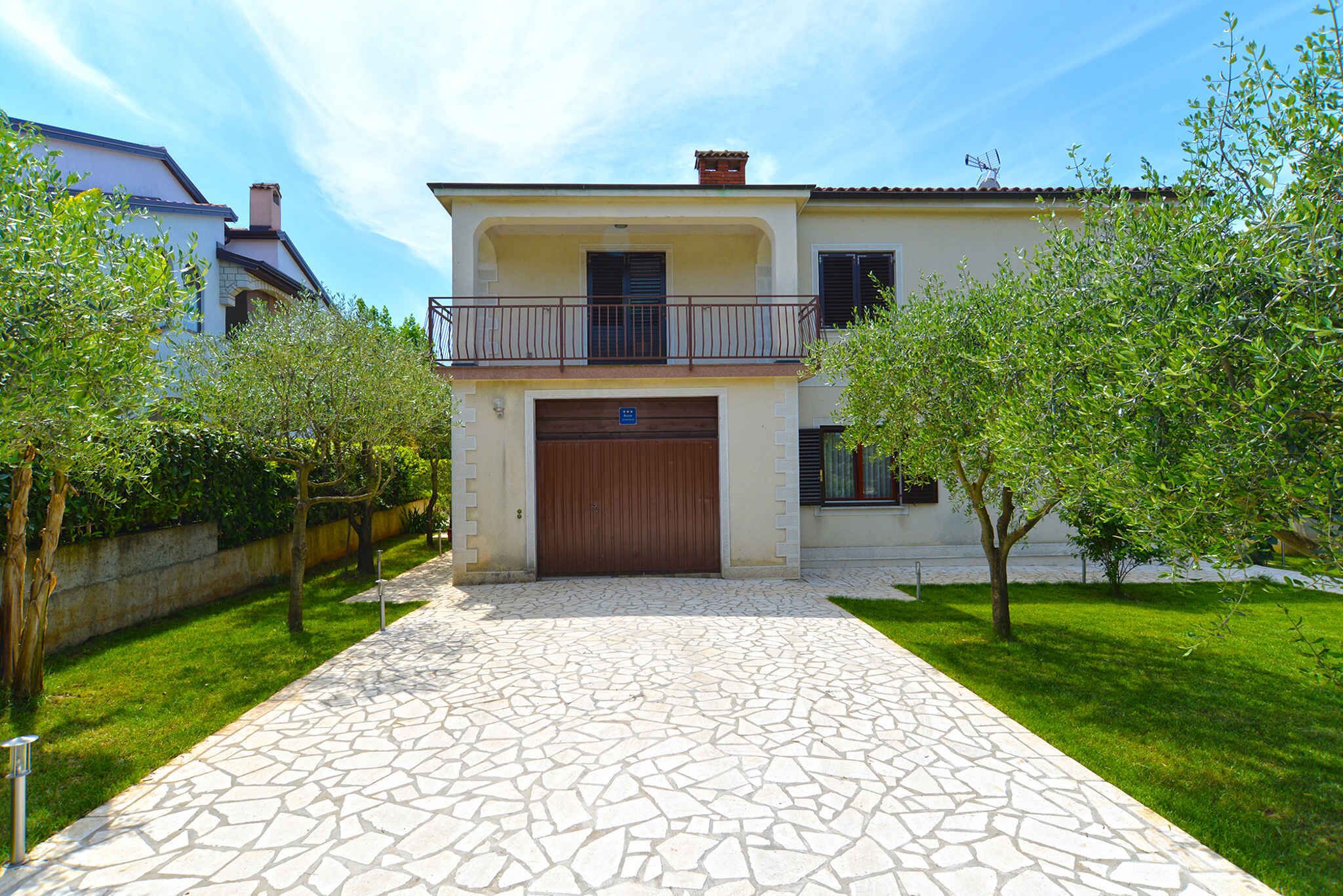 A two-story house with a stone-paved driveway leading to a wooden garage door.